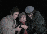 a group of three men are standing around a man in a wheelchair