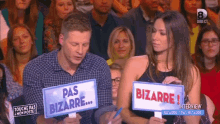 a man and a woman are holding up signs that say pas bizarre
