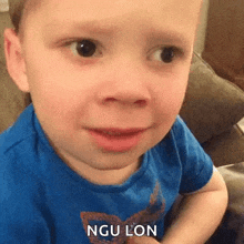 a little boy in a blue shirt is making a funny face .