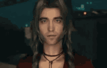a man with long hair is wearing a red shirt and a necklace .