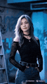 a woman wearing a choker and a black shirt stands in front of a blue wall