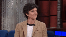 a woman in a brown jacket is sitting in a chair with a microphone .