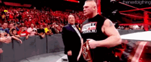 a man in a black shirt with the word atlanta on it stands in a wrestling ring .
