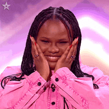 a woman in a pink shirt is smiling and covering her face