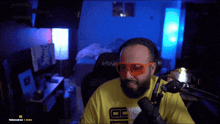 a man wearing orange glasses and a yellow shirt that says cc on it