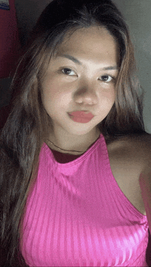 a young woman wearing a pink striped top looks at the camera