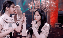 a group of girls are standing next to each other and one is holding a microphone .