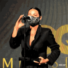 a woman wearing a mask is standing in front of a microphone