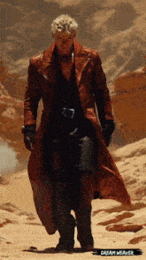 a man in a long red coat is walking in the desert with cream weaver written on the bottom