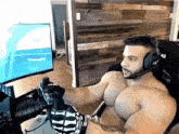 a shirtless man is sitting in a chair wearing headphones and a microphone .