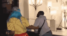 a man and a woman are fighting in a room . the woman has blue hair and the man has a beard .