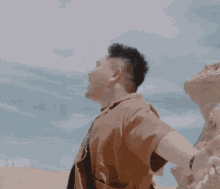 a man with his arms outstretched in front of a blue sky with chinese writing below him