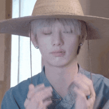 a young man wearing a straw hat with his eyes closed .