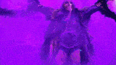 a female wrestler is wearing a mask and holding a belt in a purple room .