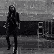 a woman is dancing in a black and white photo in a room .