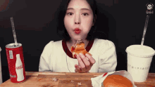 a woman is eating a hamburger next to a can of coca-cola
