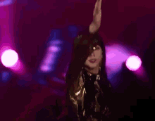 a woman in a black and gold outfit is dancing on a stage
