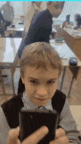 a young boy is taking a picture of himself in a classroom with his phone