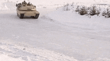 a military tank is driving on a snowy road .