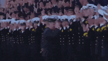 a group of military men are standing in a line applauding .