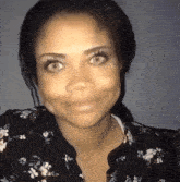 a close up of a woman 's face with a floral shirt