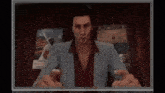 a man in a suit and red shirt is pointing at the camera while sitting in front of a television .