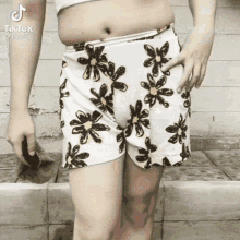 a woman wearing a white skirt with black flowers and a tik tok sticker