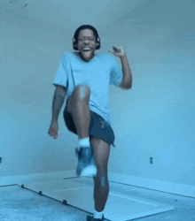 a man wearing headphones and shorts is jumping in the air with his arms outstretched