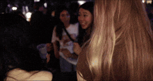 a woman with blonde hair is standing in a crowd