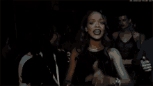 a woman in a black dress is making a funny face and pointing her finger at the camera .