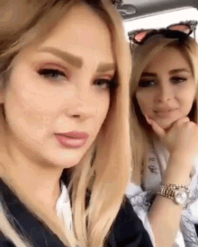 two blonde women are sitting next to each other in a car