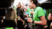 a woman in a green shirt is giving a high five to a group of people