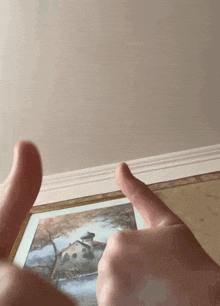 a person giving a thumbs up in front of a picture of a house