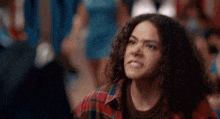a woman with curly hair wearing a plaid shirt is making a funny face