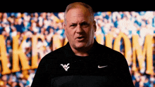 a man wearing a nike shirt is standing in front of a crowd of people .