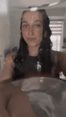 a woman is taking a selfie in a bathtub while looking out the window .