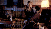 a man and woman are kissing in a living room with a bottle of vodka on the table