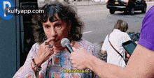 an elderly woman is being interviewed by a man with a microphone .