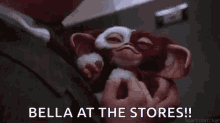 a man is holding a stuffed animal with the words `` bella at the stores '' written above it .
