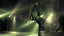 a man is dancing on a stage in a dark room with green lights .