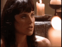 a naked woman is sitting in front of a candle .