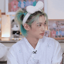 a young man with blue hair wearing a white bunny headband