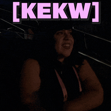 a woman is smiling in a dark room with the words [ kekw ] above her