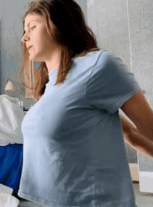 a woman in a blue t-shirt is standing in a room