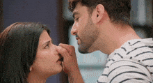a man is touching a woman 's nose while they look at each other .
