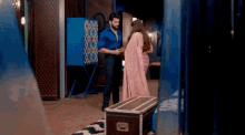 a man and a woman are standing in a room next to a trunk .