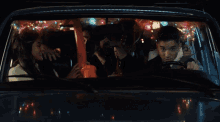 a group of people sitting in a car with christmas lights on the roof