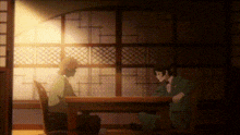 two men are sitting at a table in a dark room talking on a cell phone .
