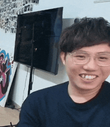 a man with glasses is smiling in front of a television