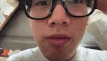 a close up of a person wearing glasses with a white shirt